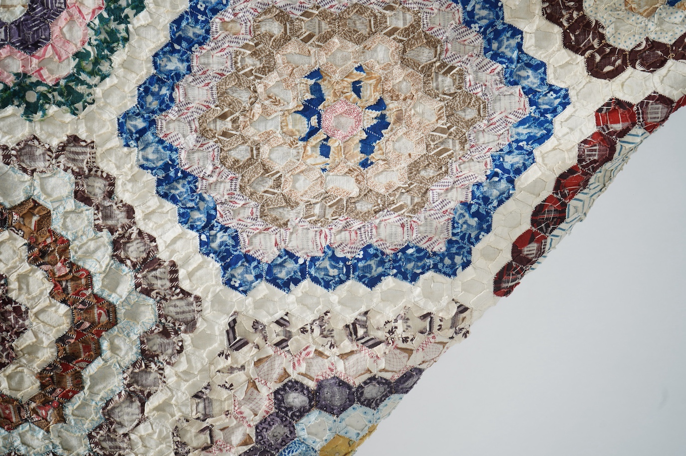 A large 19th century ‘Grandmother’s Flower Garden’ cotton patchwork bedspread, using dress fabric scraps from the day to create hexagonal concentric patterns which form a flower like shape/pattern, 282 x 254cm. Condition